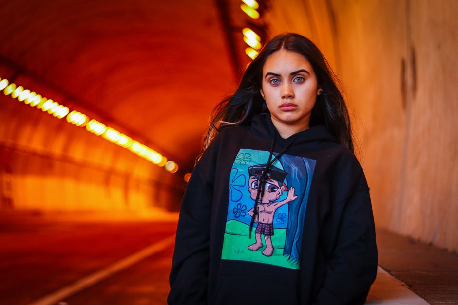 Young woman with a graphic hoodie in a vibrant tunnel setting.