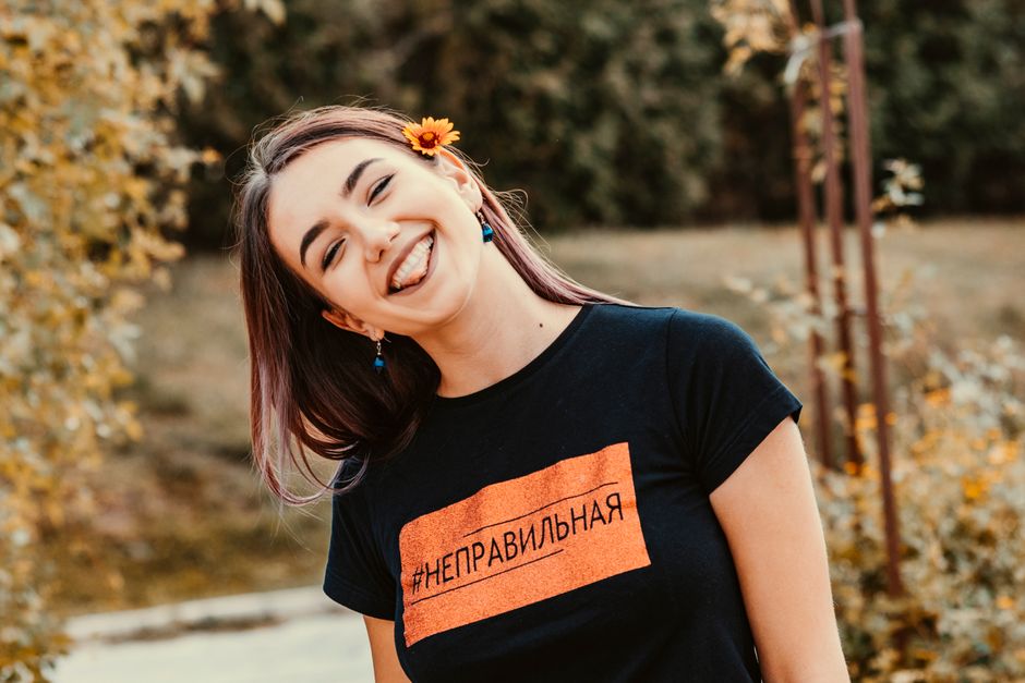 Cheerful woman with a flower in her hair smiling in an outdoor garden setting.