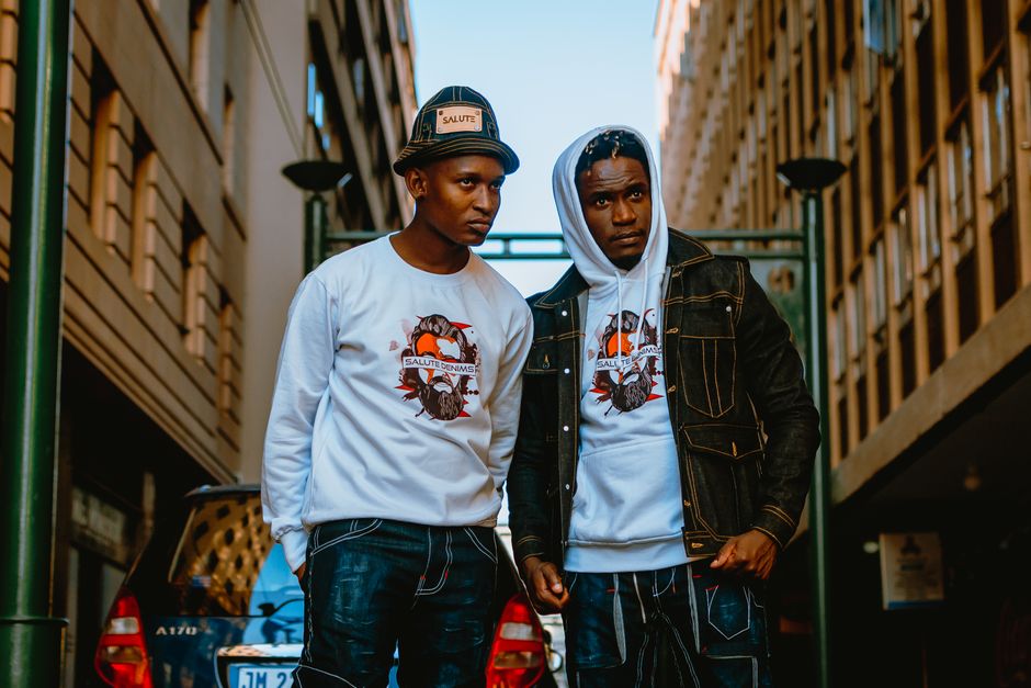Stylish urban portrait featuring two men in streetwear apparel on a city street.