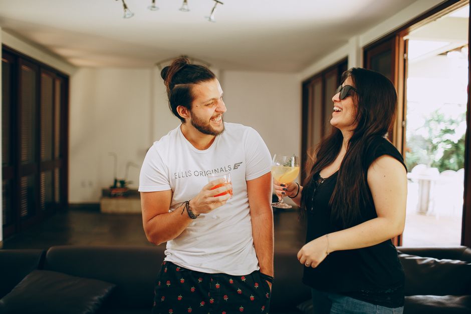 Smiling young couple in casual wear meeting in modern living room and enjoying communication with each other on weekend