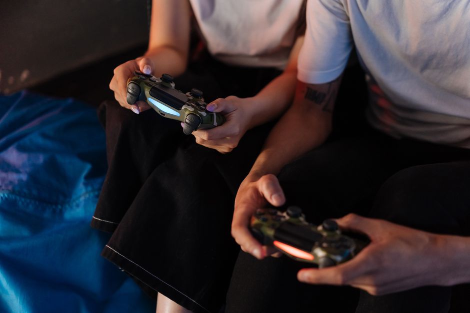 Two young adults gaming with controllers, captured in a cozy indoor setting.
