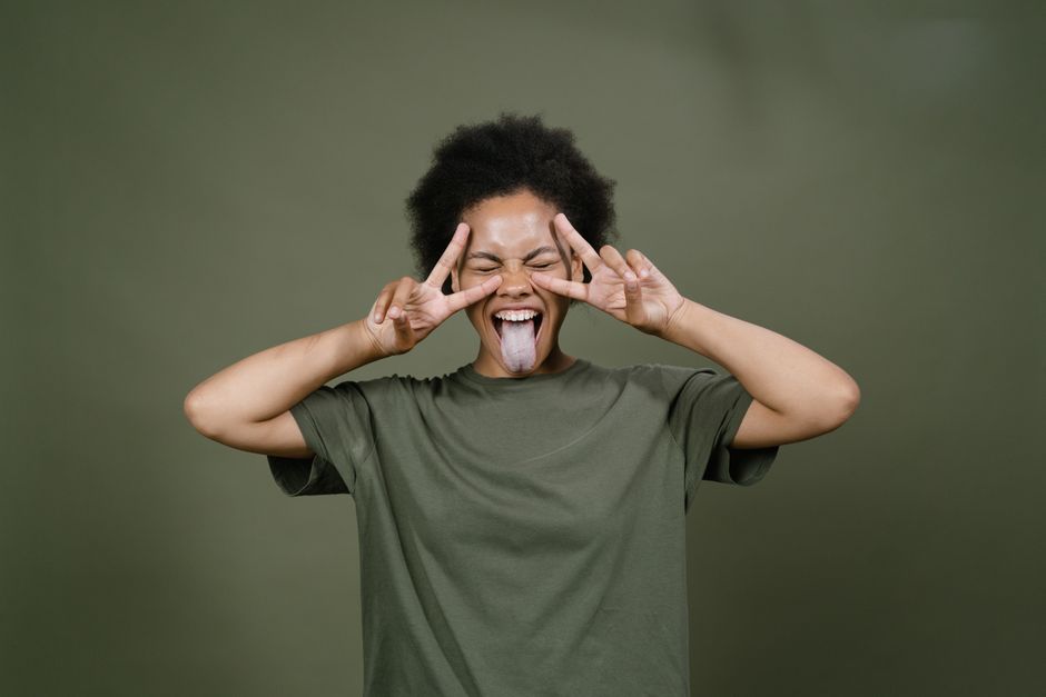 Energetic woman with afro hair joyfully posing with playful expressions and peace signs.