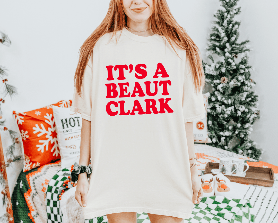 Garment-Dyed Heavyweight Unisex T-Shirt (Comfort Colors 1717) with bold holiday quote text reading "IT'S A BEAUT CLARK"