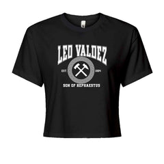 Crossed-hammers forge badge with Leo Valdez, "Son of Hephaestus," and "EST. 1994" on a Women's Boxy Crop T-Shirt