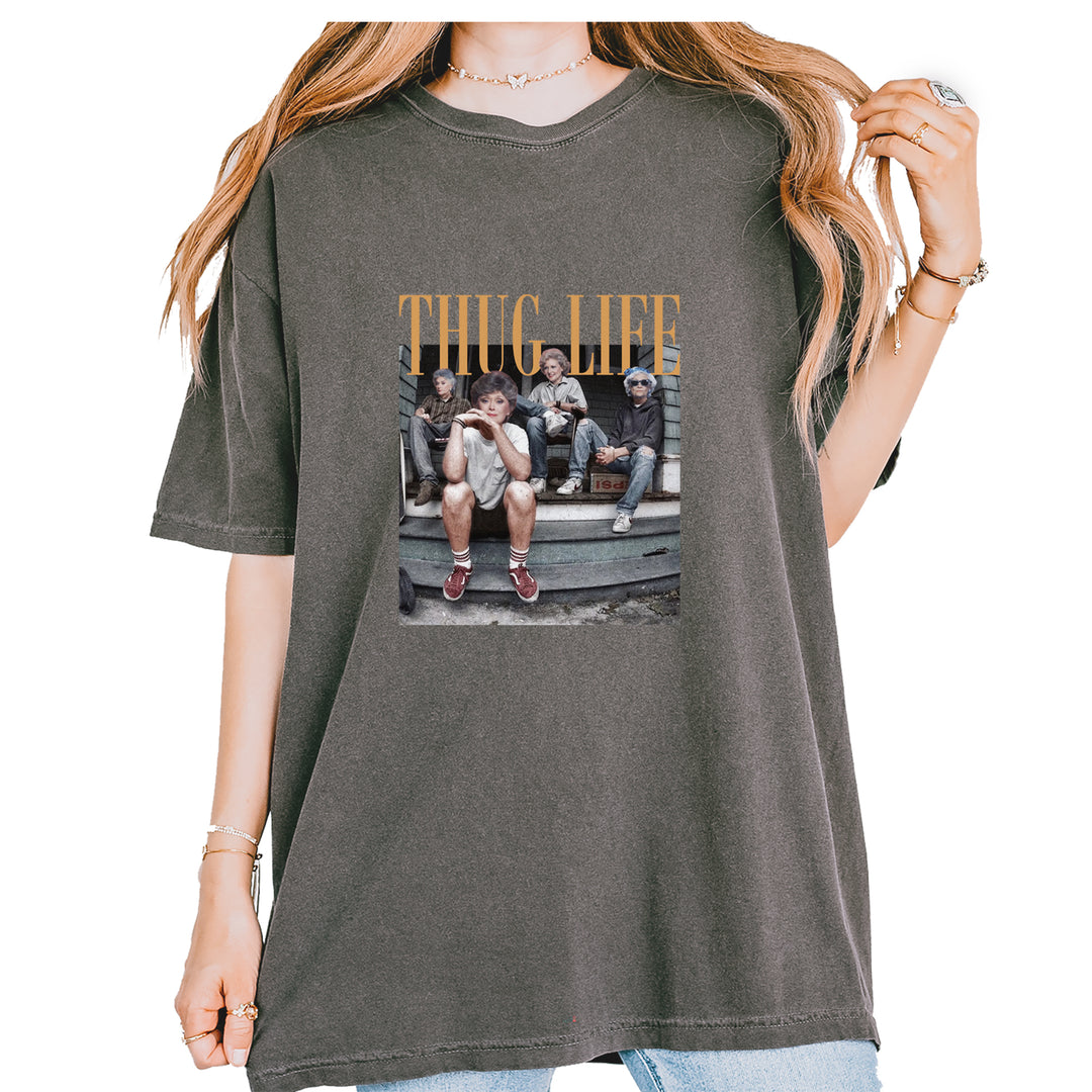 Garment-Dyed Heavyweight Unisex T-Shirt featuring "THUG LIFE" text above an older-ladies stoop squad illustration